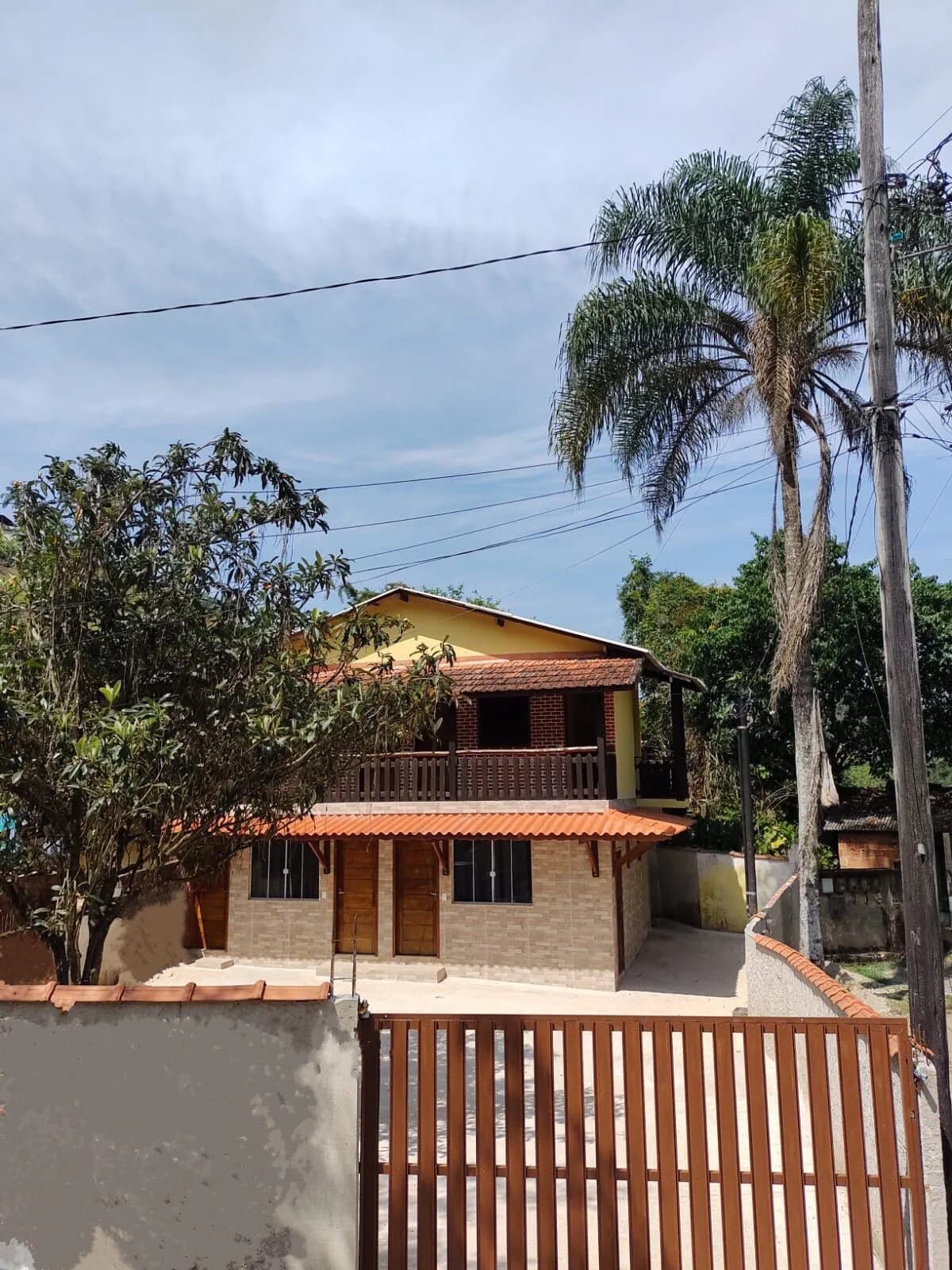 Fachada do Cantinho do Vale entre árvores e palmeiras